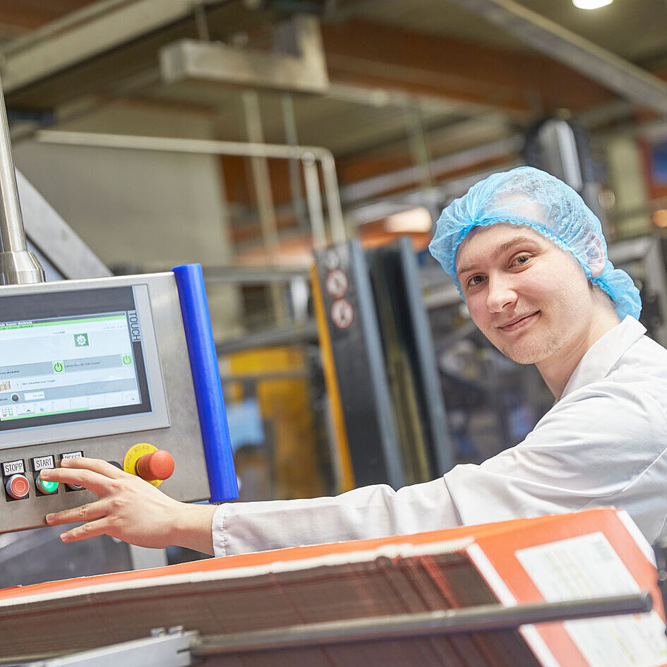 Mitarbeiter steht in der Produktion an einer Anlage 